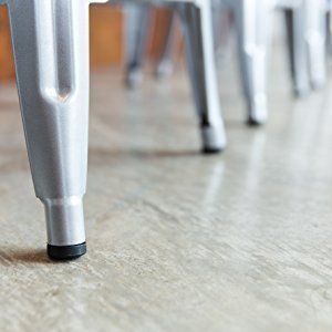 Close-up of several silver chair legs with black feet, lined up on a light-colored floor.