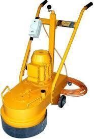 Yellow industrial concrete grinder with handle and wheels.