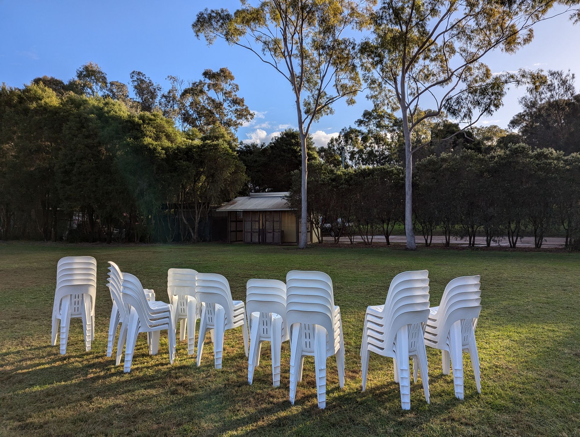 White plastic chairs stacked and in a row outdoors. White plastic chairs stacked and in a row outdoors.