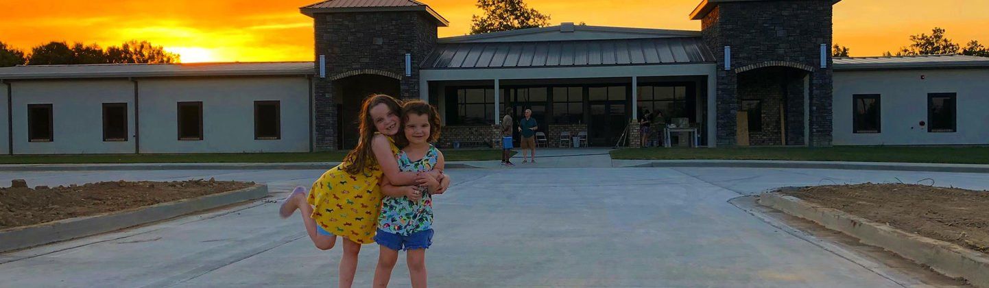 Two Little Girls Hug & Smile in Front of Victory Church in Columbia, MO