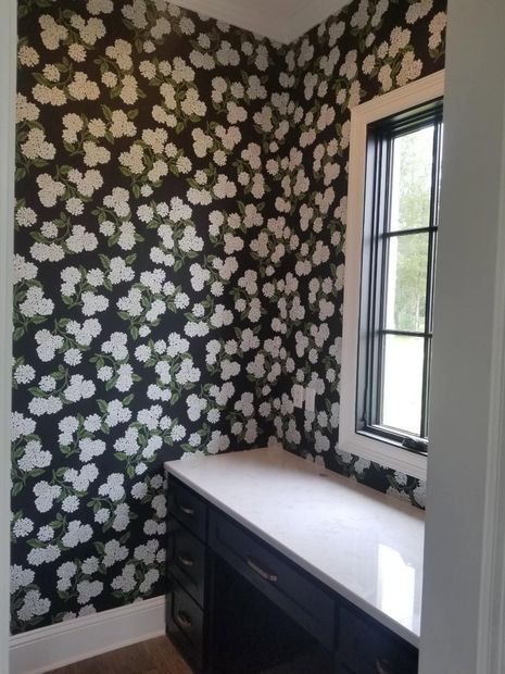 Nursery bedroom with white crib, dresser, pink curtains, floral wallpaper, and light blue wainscoting.
