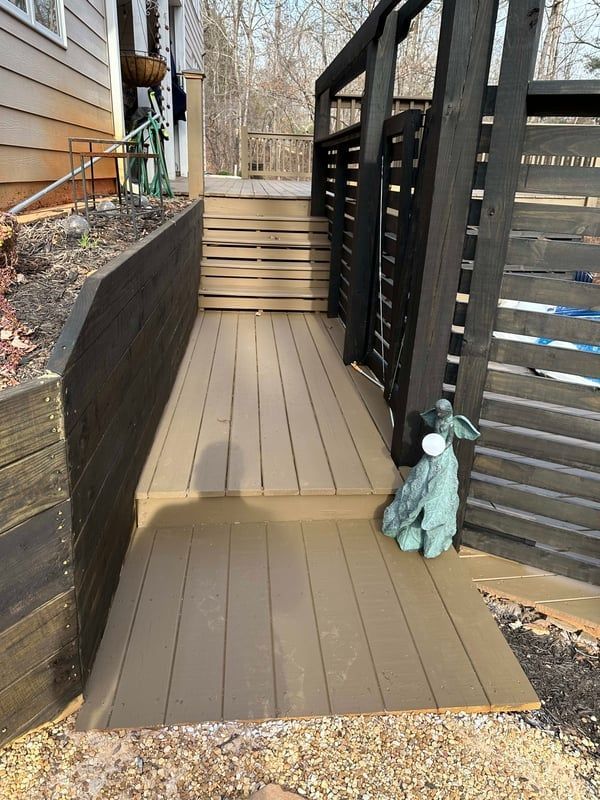 Wooden deck and steps leading to a black-fenced outdoor space. A blue statue of an animal is placed on the deck.