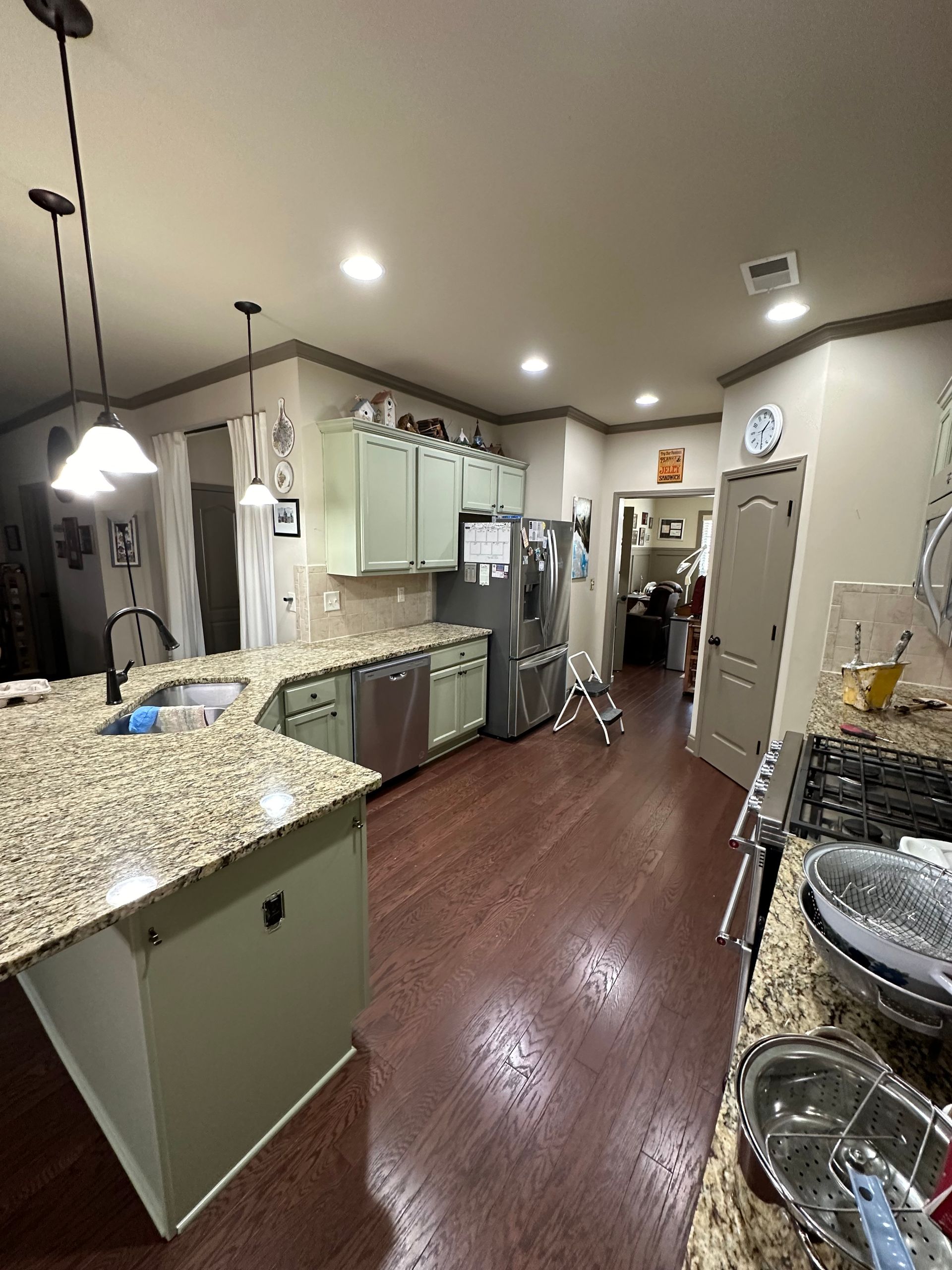 Kitchen with green cabinets, granite countertops, and dark wood floors.