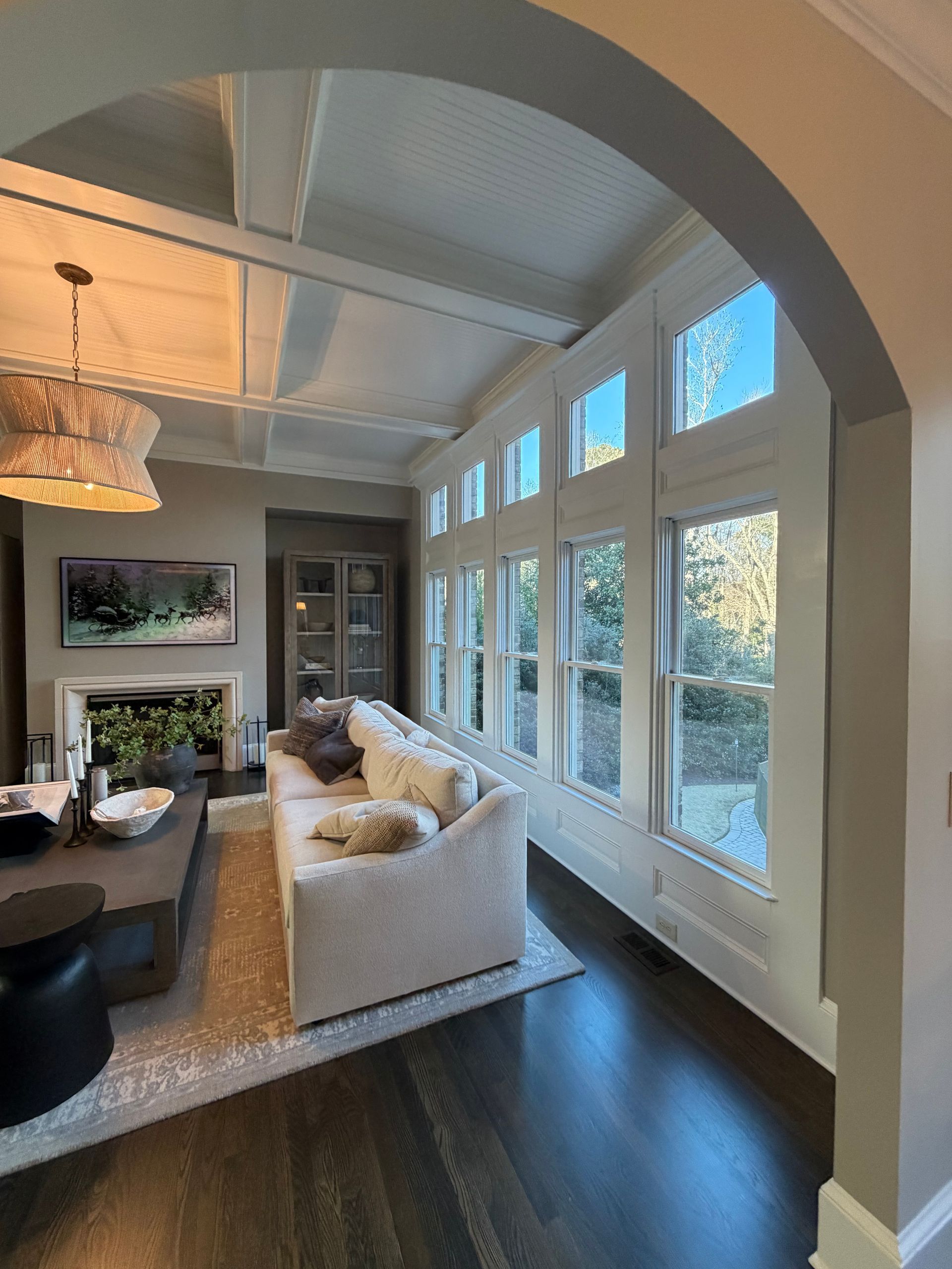 Living room with a row of windows, a white sofa, and a dark wood floor.