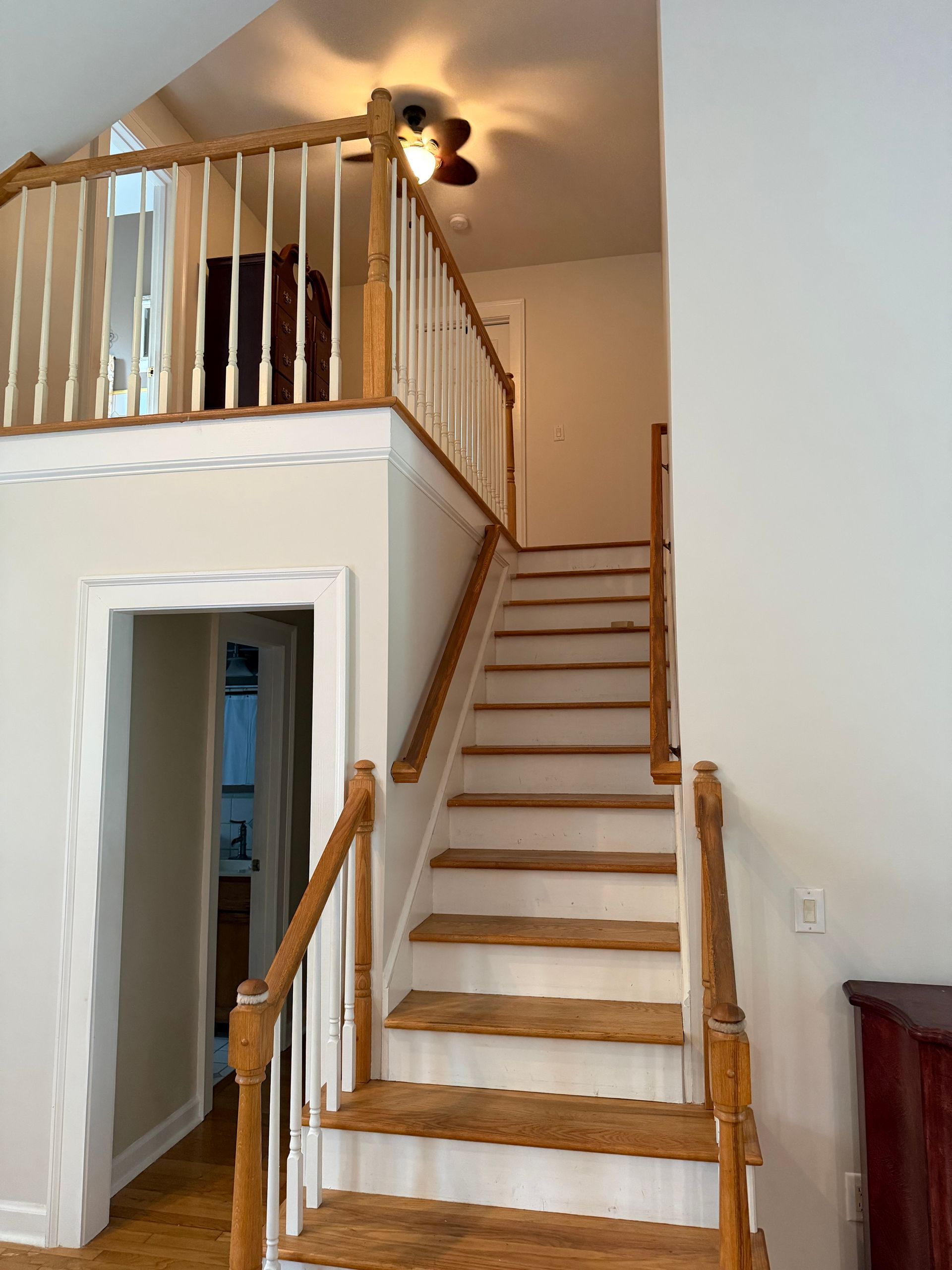 Interior staircase with wooden railings leading to a loft landing and hallway below
