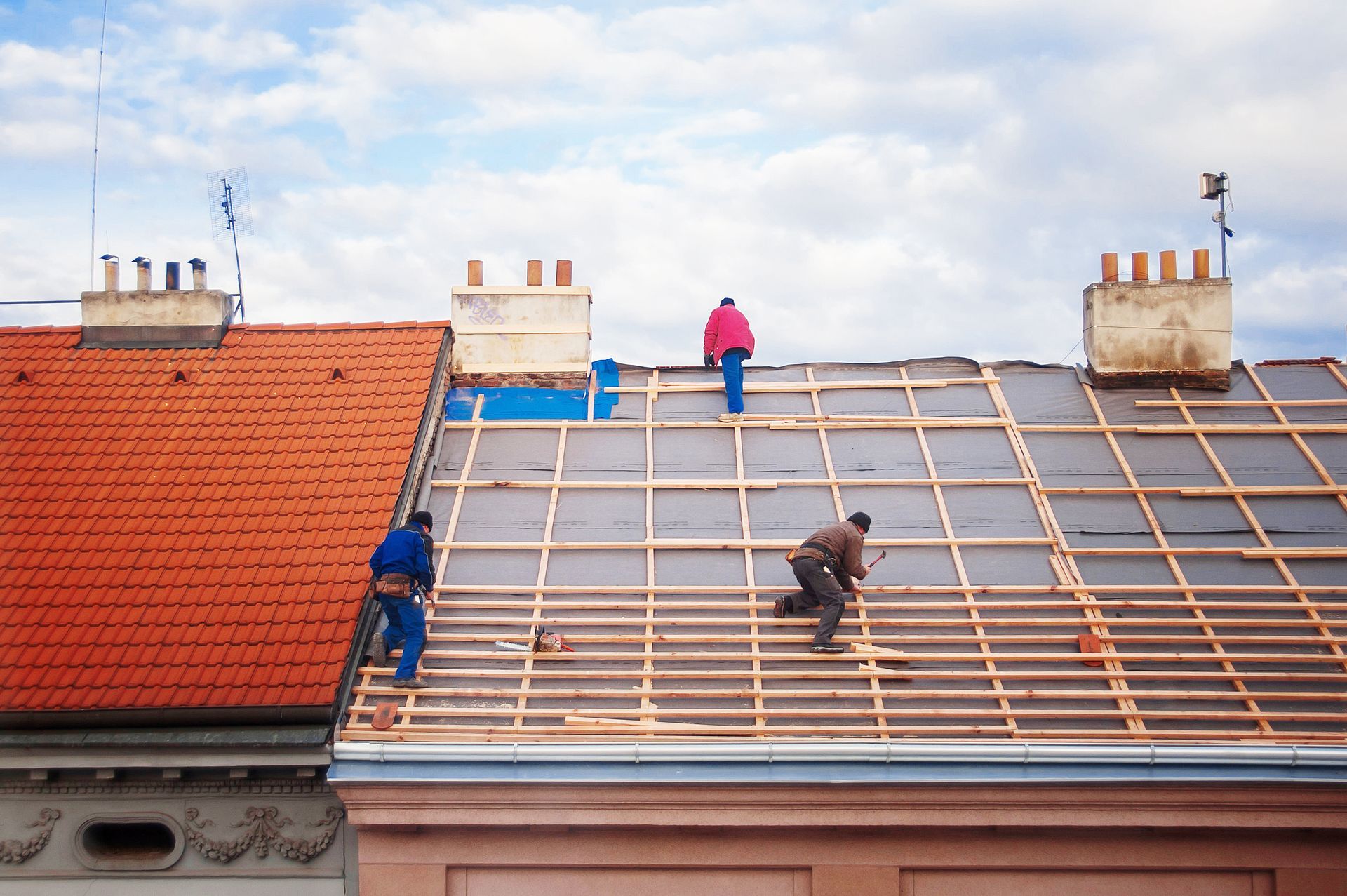 Roofers installing wooden battens during a residential roof replacement project.