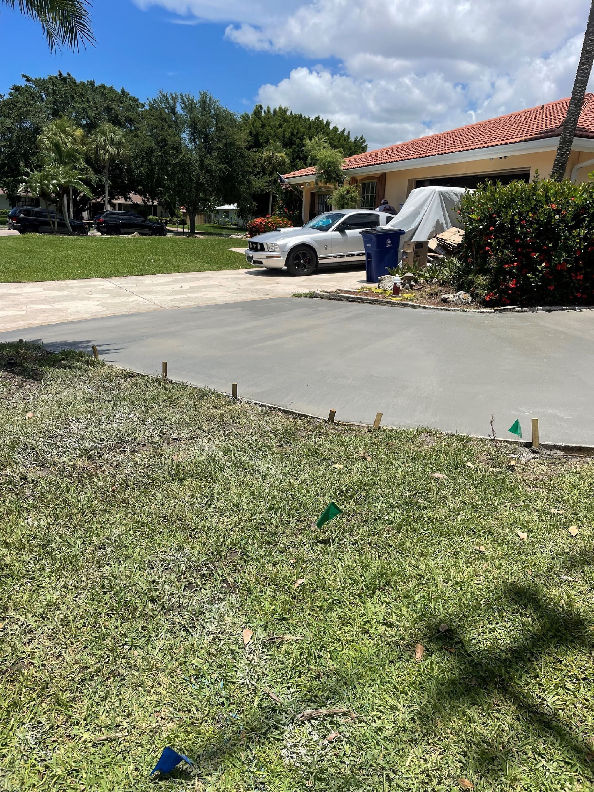 Driveway with a car, next to a house, on a sunny day.