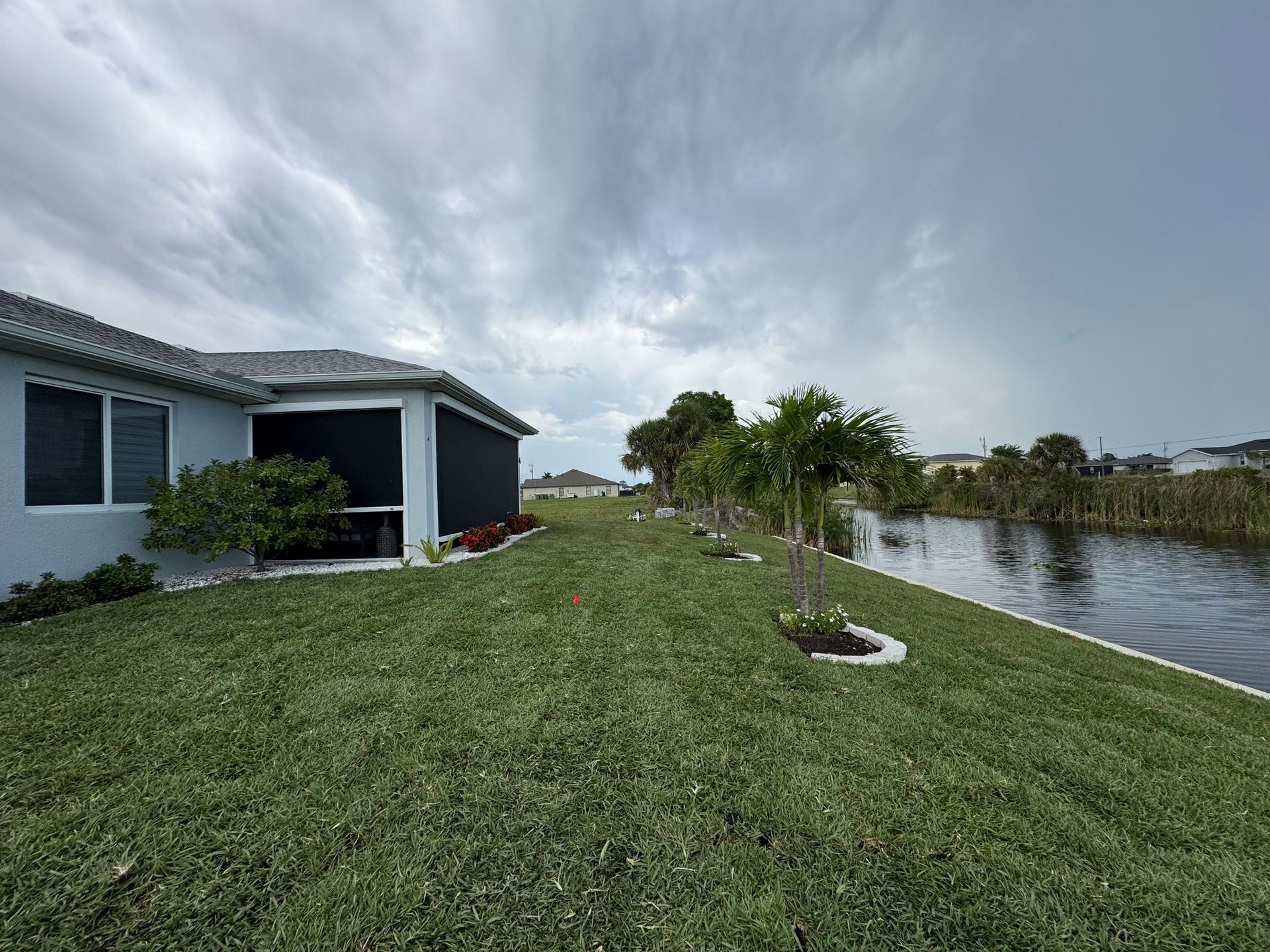House beside a canal with a grassy yard and cloudy sky