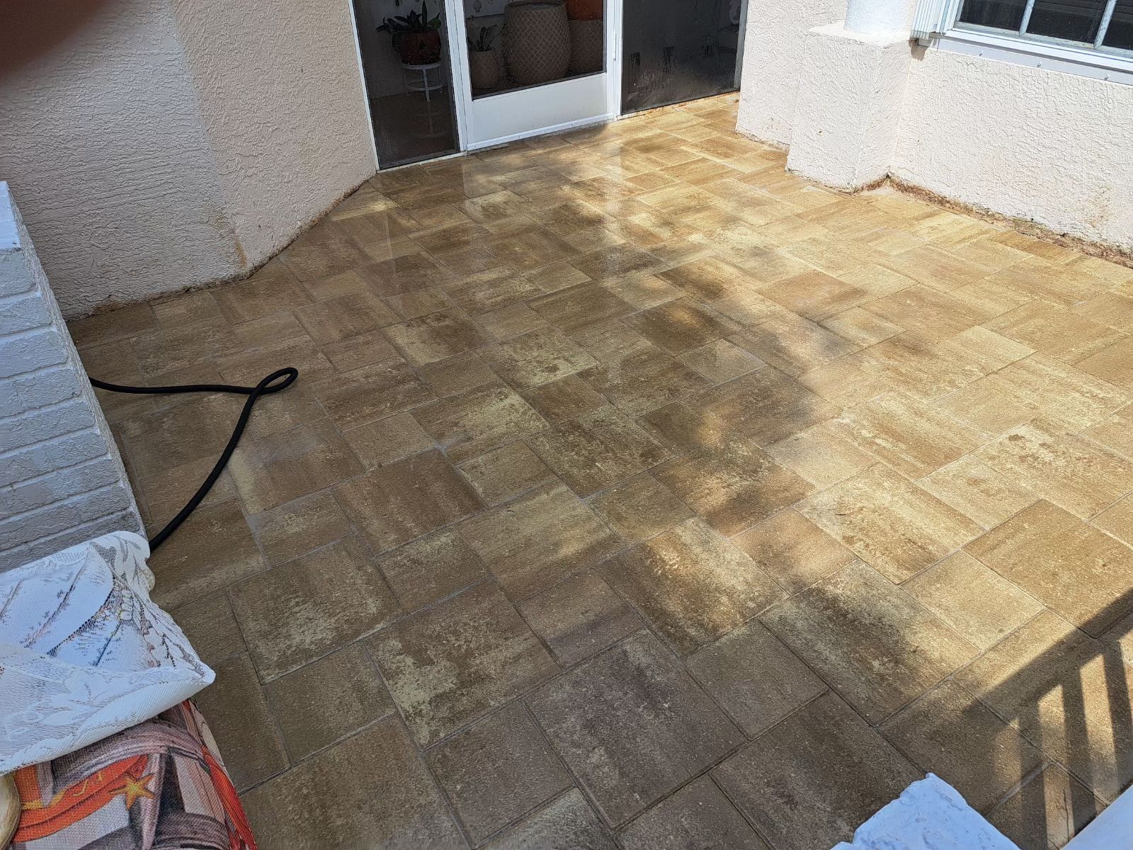 Patio with brown tile flooring and light beige walls, seen in natural lighting.