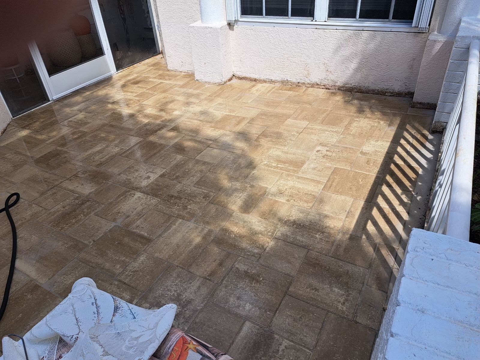 A tiled porch area with a partly open door, window, and white railing.