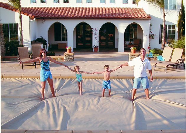 Family holding hands on a beach blanket in front of a white villa with arches at sunset
