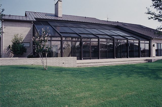 Single-story house with a glass-enclosed patio and a green lawn