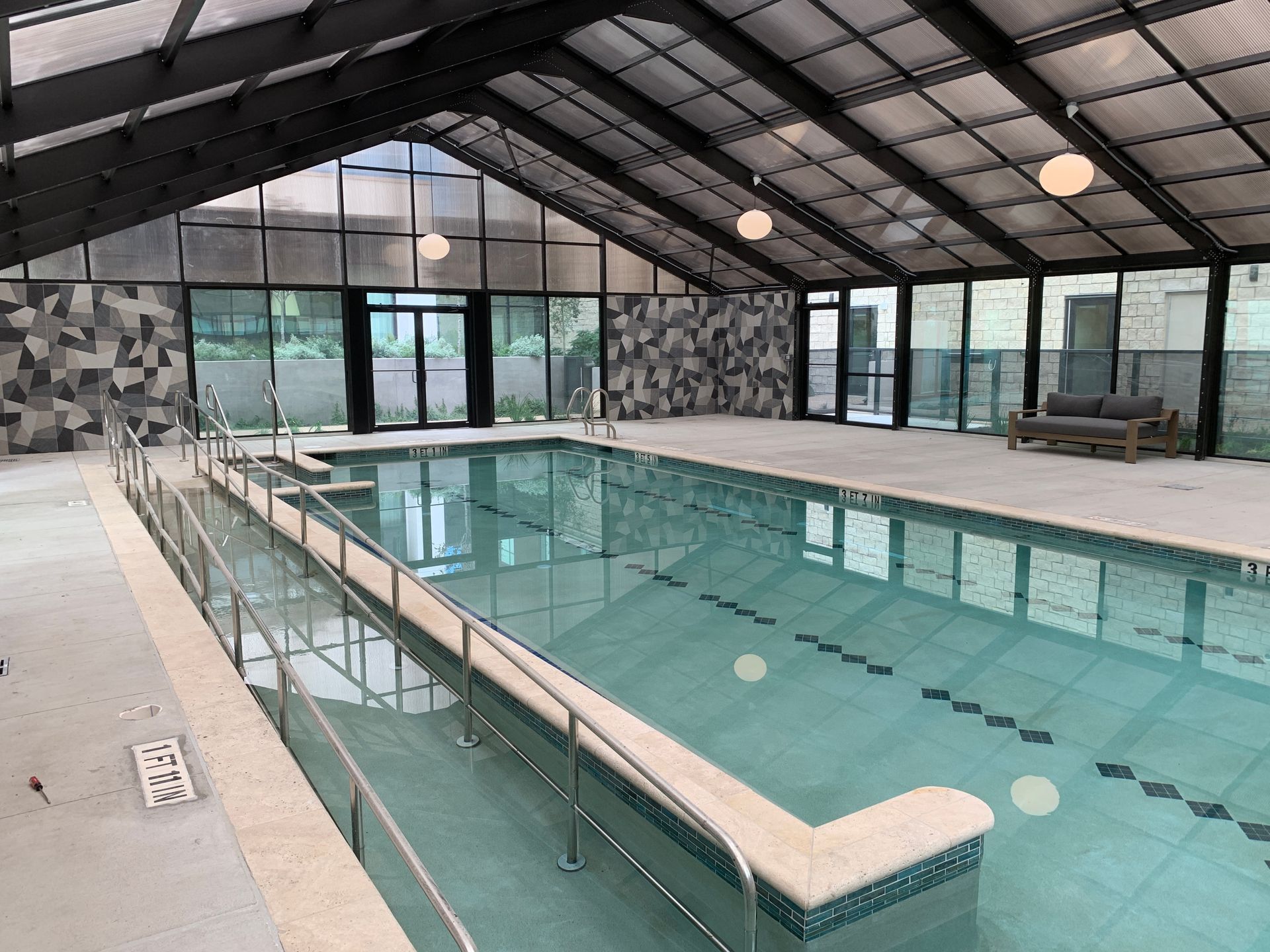 Indoor swimming pool with lane ropes, glass walls, and a sloped ceiling