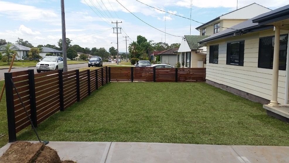 A Grassy Front Yard is Enclosed by a Brown Horizontal Slat Fence — Creating Eden Landscaping In Speers Point, NSW