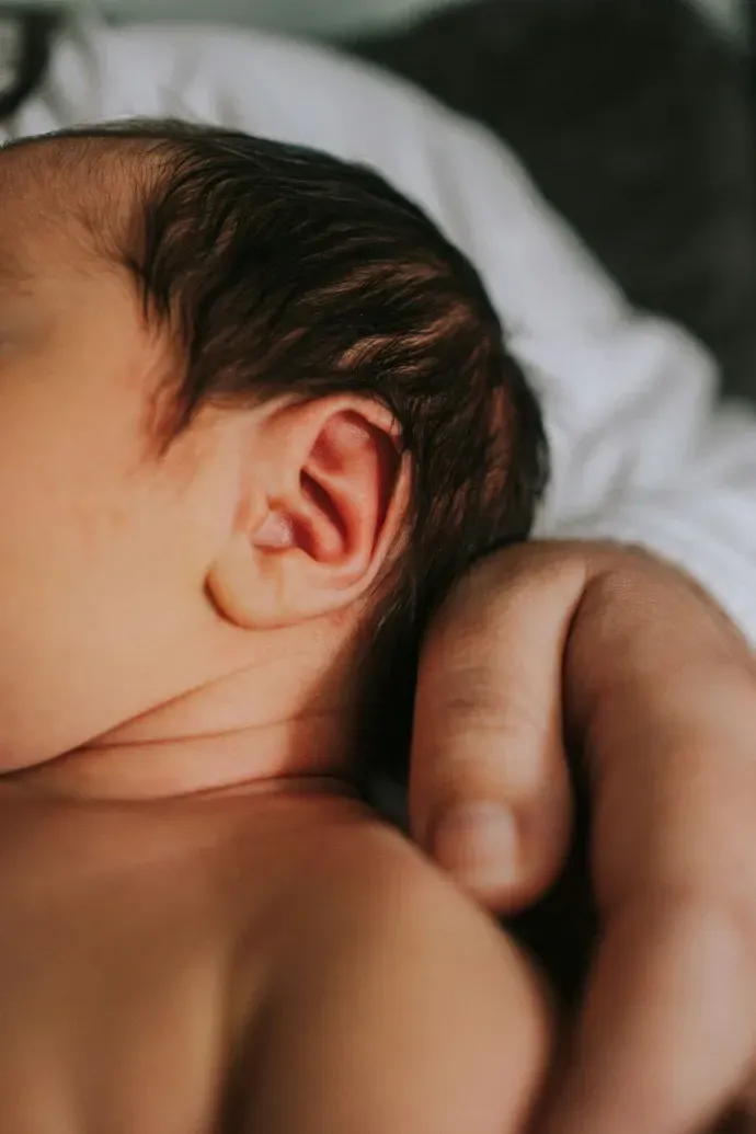 Bambino addormentato che riposa su un cuscino bianco, ripreso da vicino di profilo.