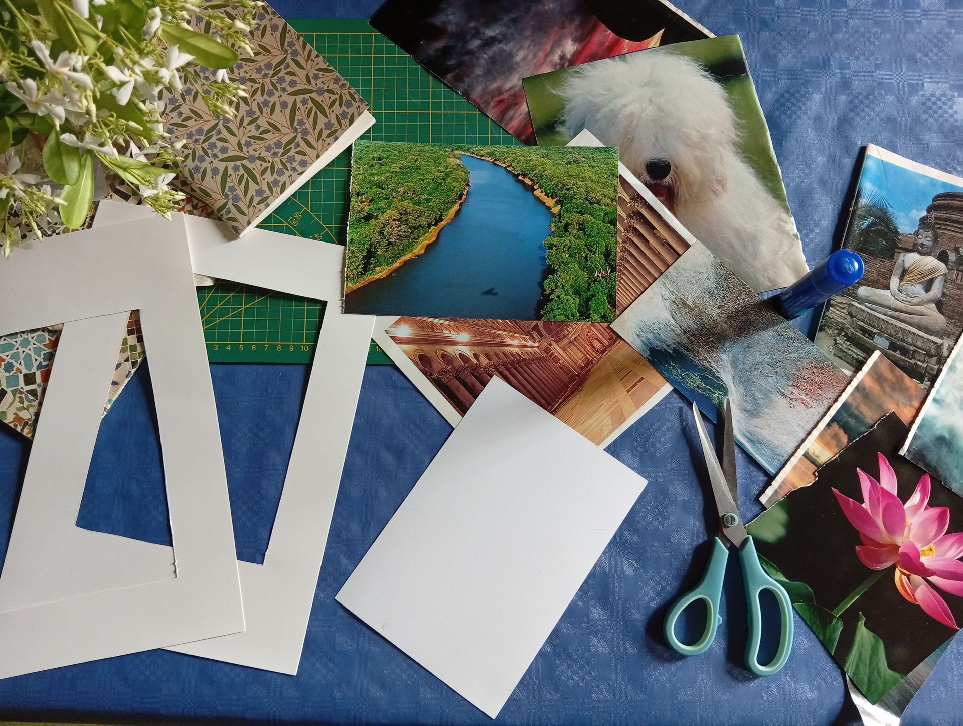 Cornici di carta, foto e forbici da bricolage sparse su una superficie blu, a suggerire la composizione di un album di ritagli.