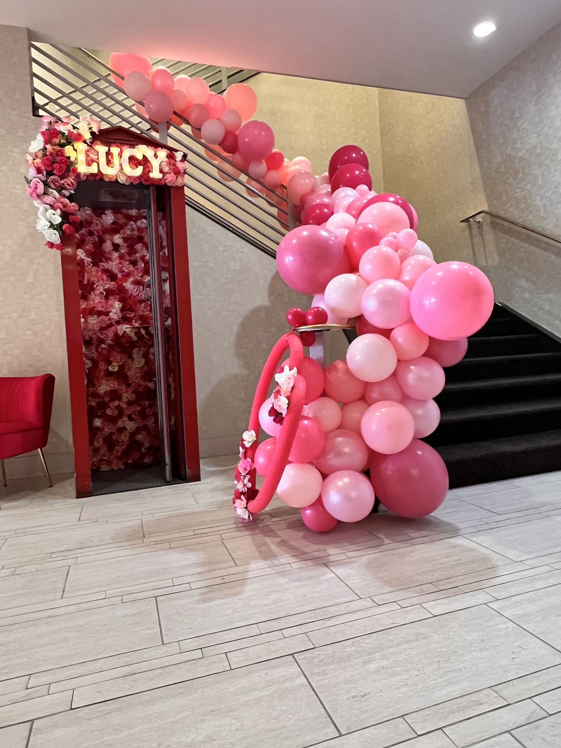 A staircase with pink balloons and a sign that says lucy