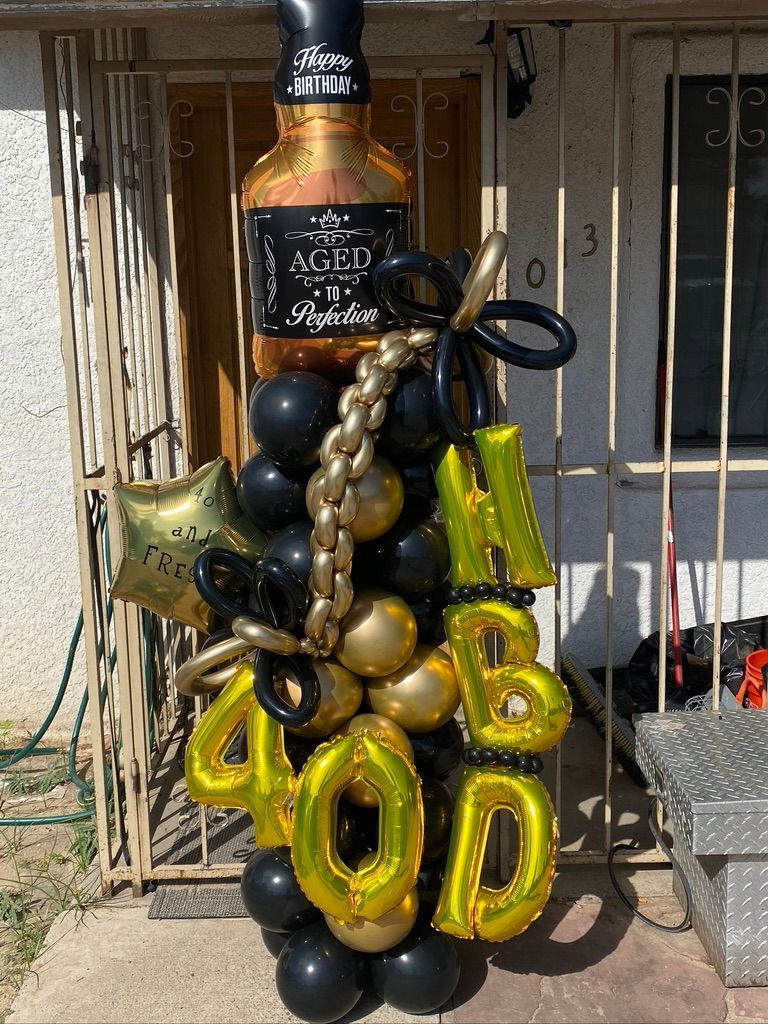 A bottle of jack daniels is surrounded by balloons and a chain.