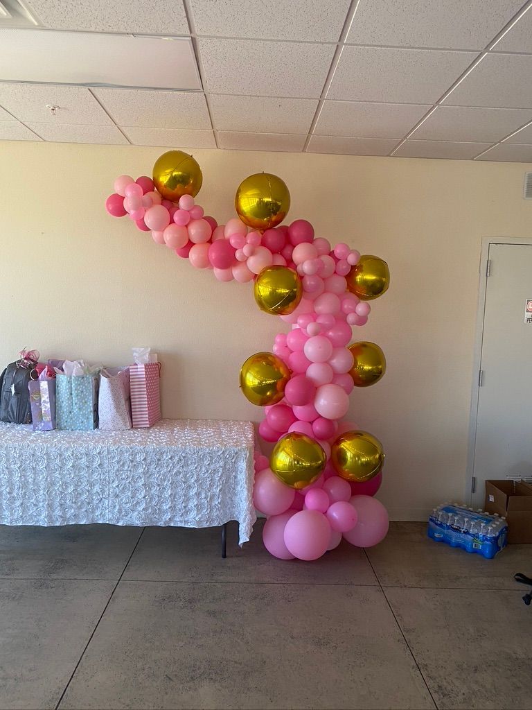 A room filled with pink and gold balloons and a table.