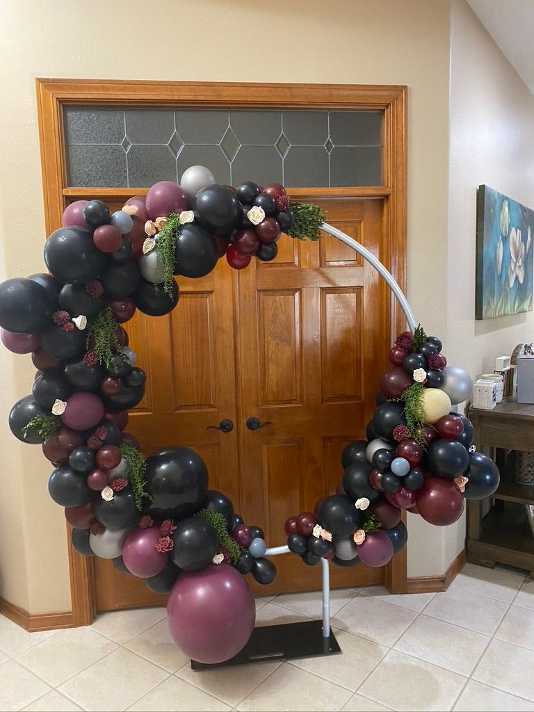 A balloon arch is sitting in front of a door in a room.