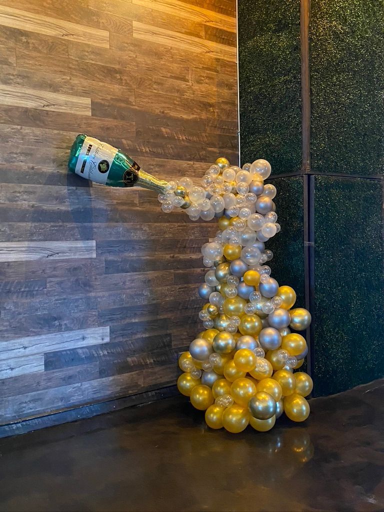 A bottle of champagne is being poured out of a balloon.