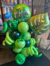 A bunch of colorful balloons are sitting next to a tree.