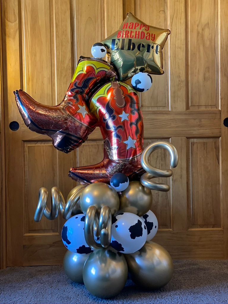 A cowboy boot balloon is sitting on top of a bunch of balloons.