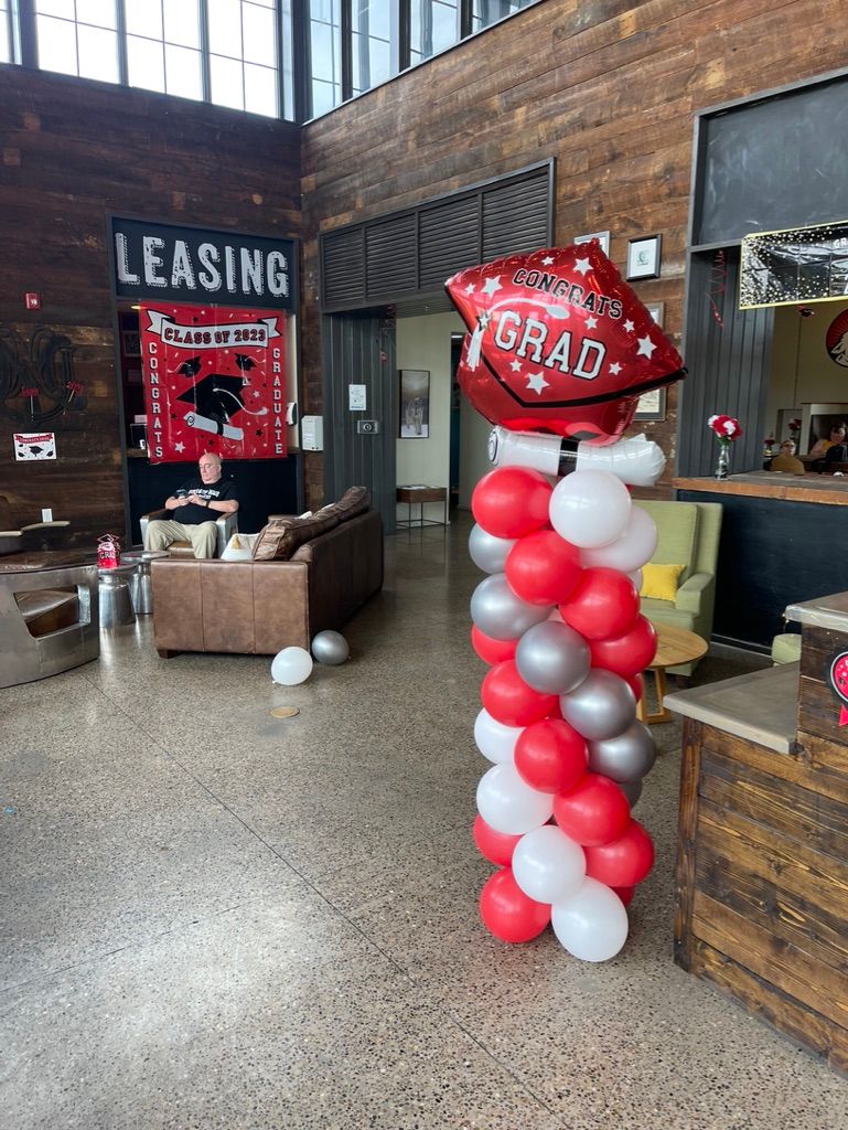 A balloon tower with red , white and silver balloons in a living room.