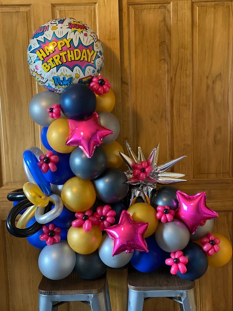 A bunch of balloons are sitting on a stool in front of a wooden door.
