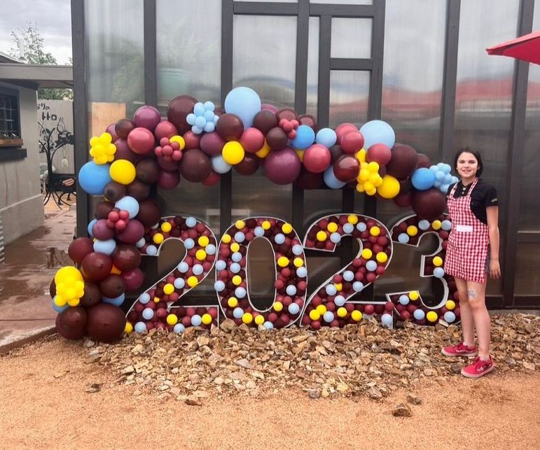 A girl is standing in front of a sign that says 2023