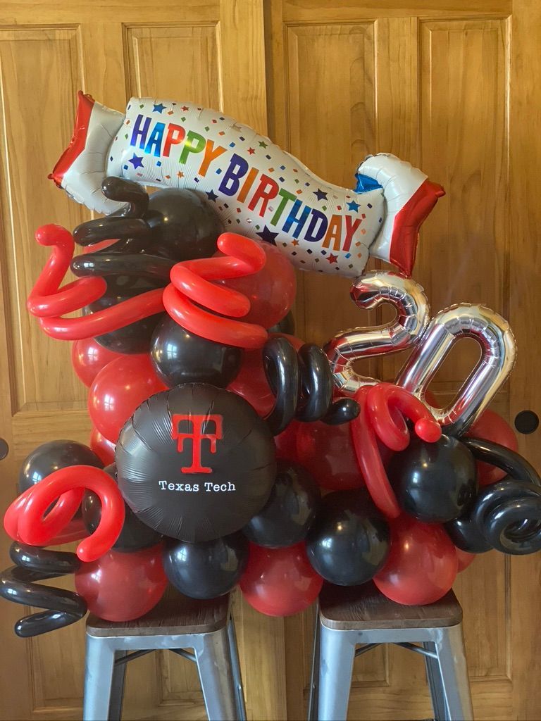 A bunch of red and black balloons are sitting on a stool.