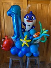 A bunch of colorful balloons are sitting next to a tree.