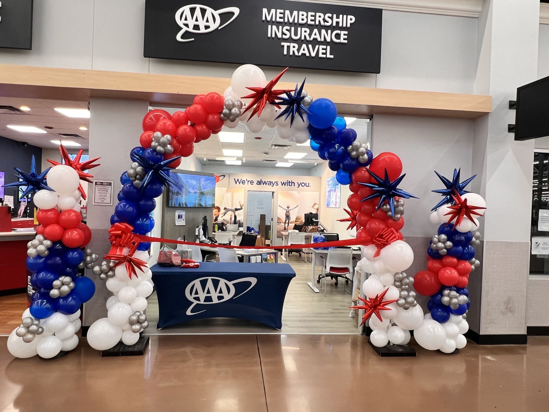 A store front decorated with red , white and blue balloons.