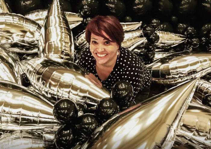 A woman is laying in a pile of gold balloons