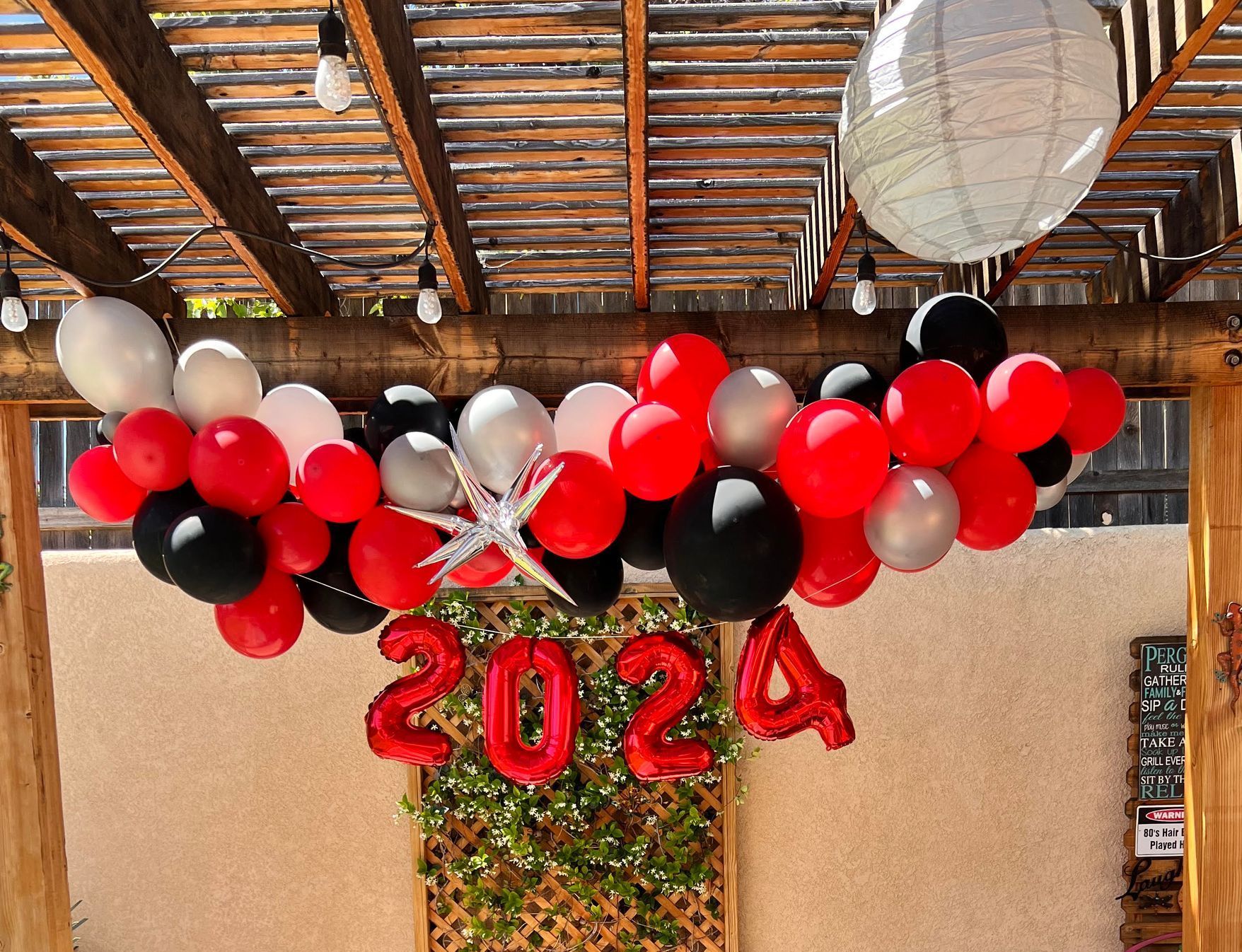 A blue couch is under a pergola with balloons hanging from the ceiling.