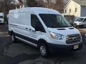 White Ford Transit van parked outside a building, with a license plate visible.