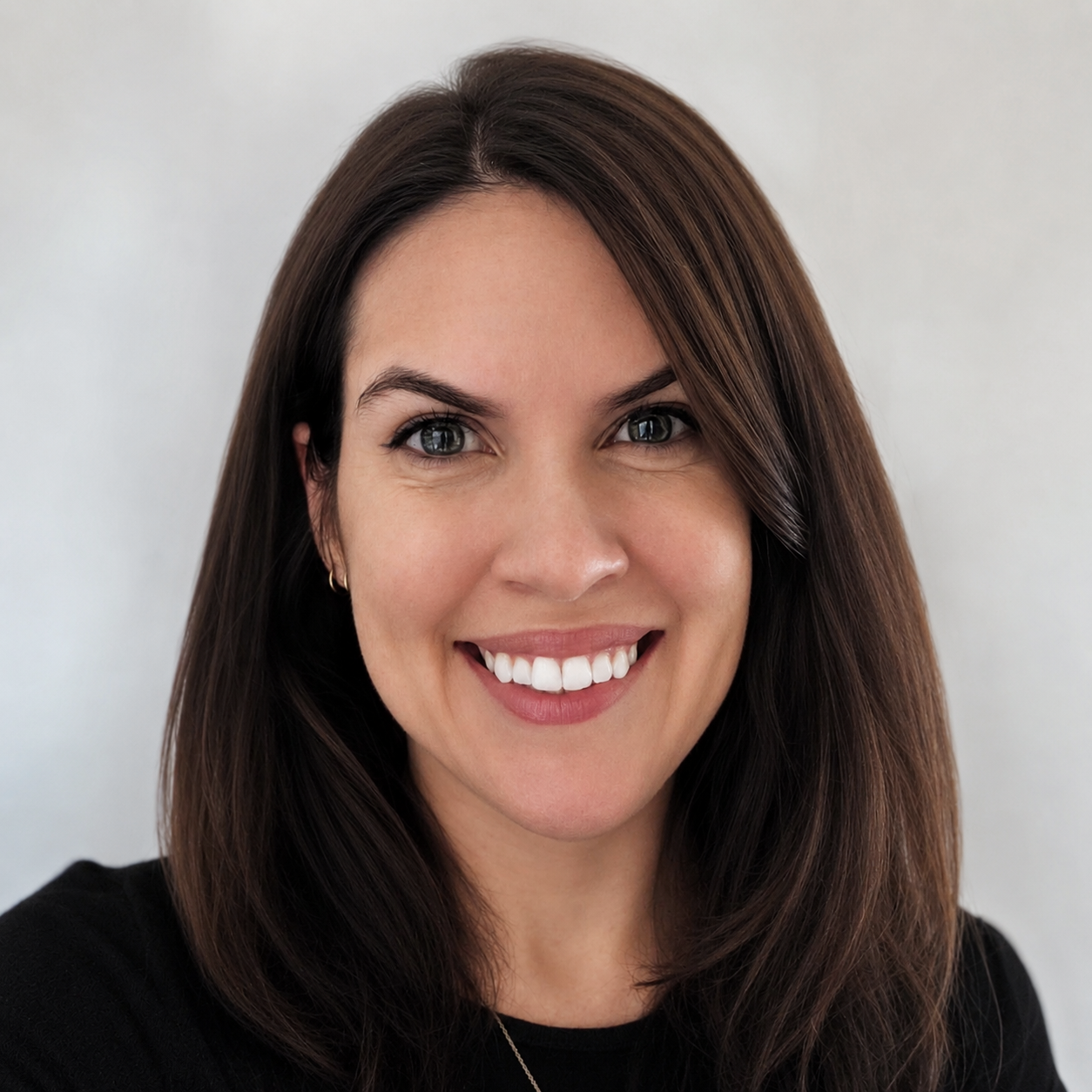 Woman with dark hair, smiling, and  wearing a black shirt against a white background.