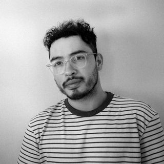 Man with glasses and beard, wearing striped shirt, looking at camera.