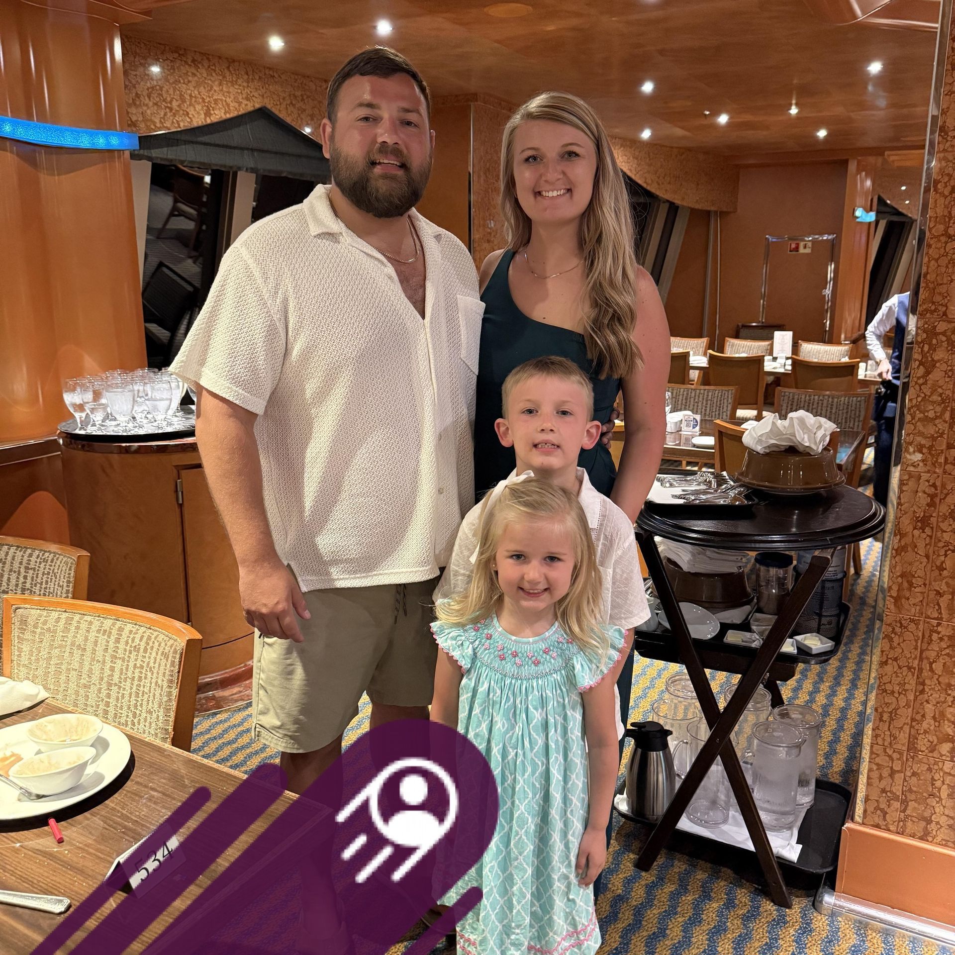 Family of four posing indoors at a warmly lit event, with tables and chairs in the background, with client Daniel Troutman pictured on the left side with his family. 