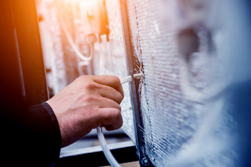 Our Services Hand plugging a white cable into a large outdoor device with frosty blue surface