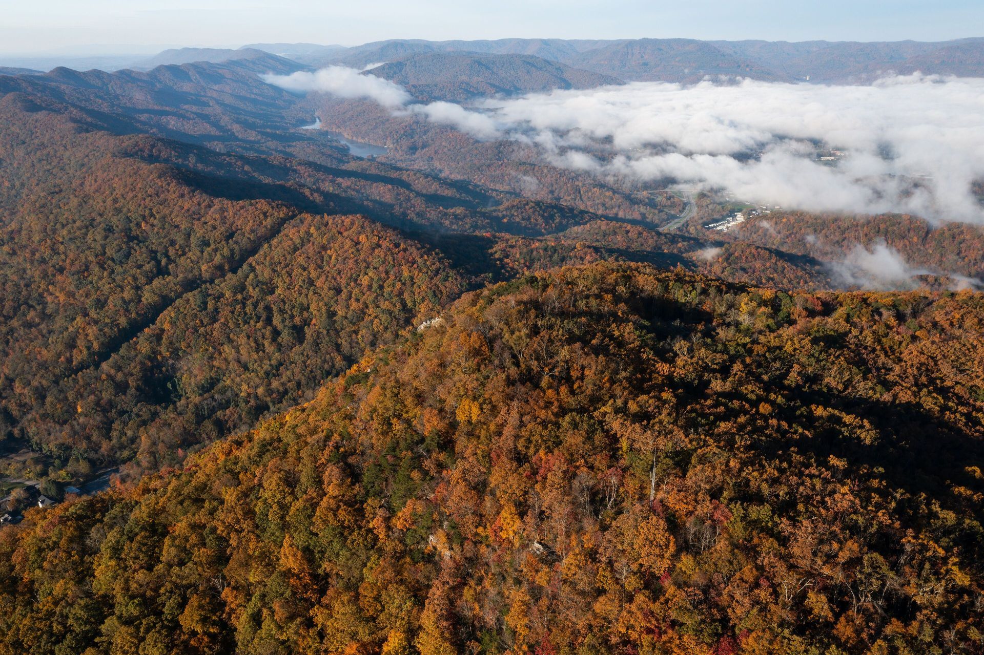 Aerial view of autumn-colored mountains with rolling clouds in the distance in White Pine, Tennessee.