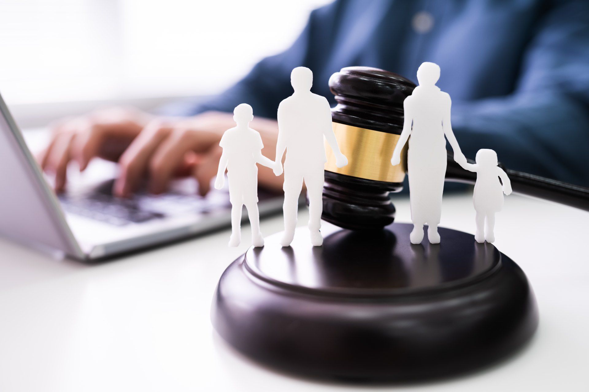 A man is typing on a laptop next to a gavel with a family on it.