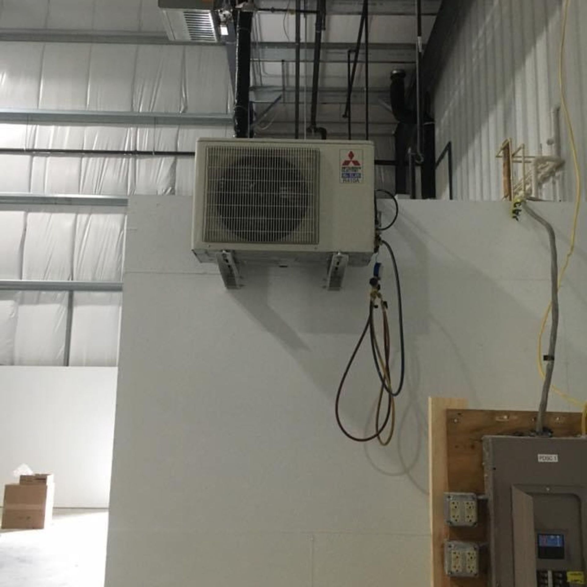 Lake Area Heating and Cooling LLC | A white air conditioner is hanging on a white wall in a building.