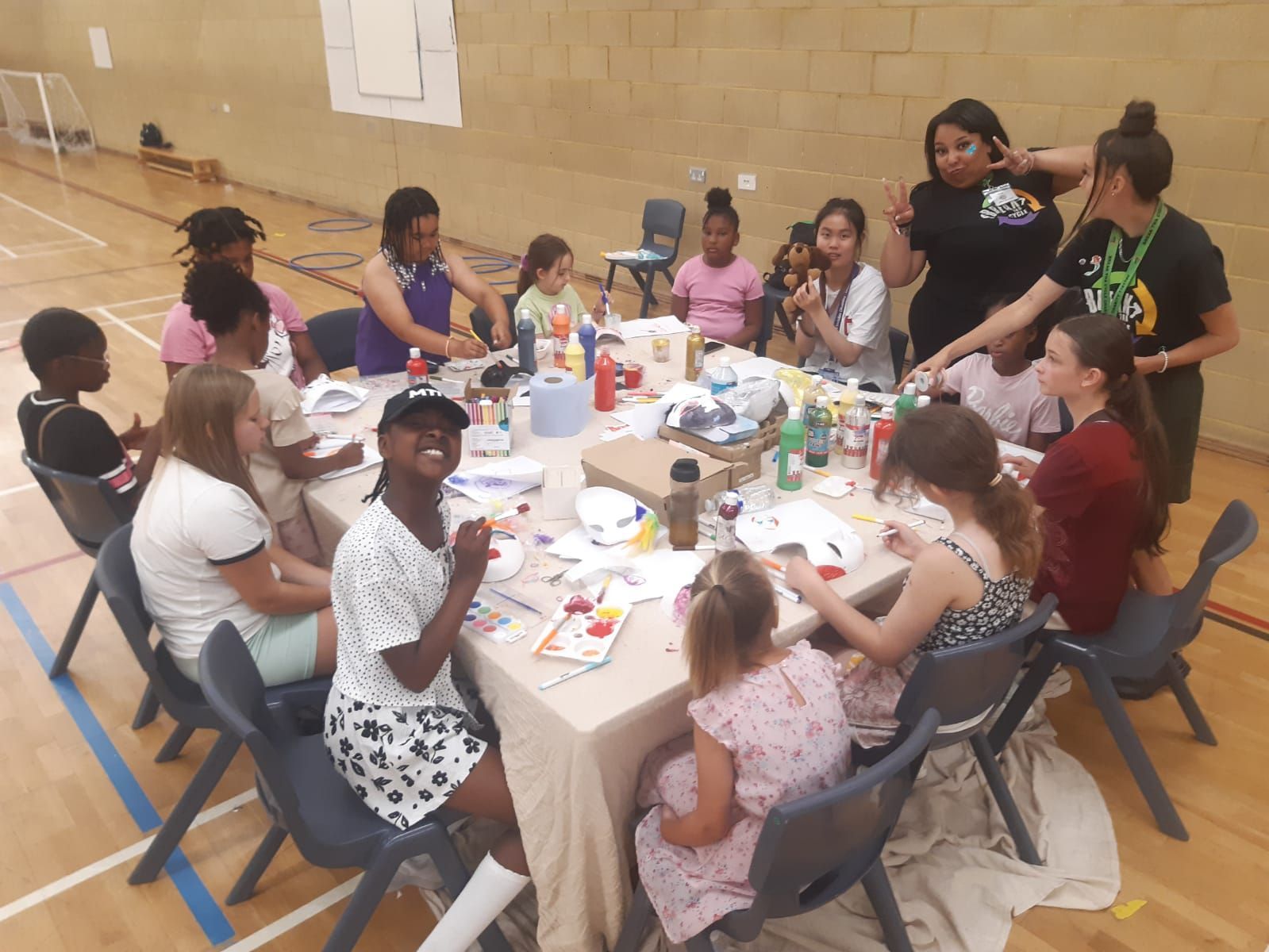 A group of people are sitting around a table in a gym.