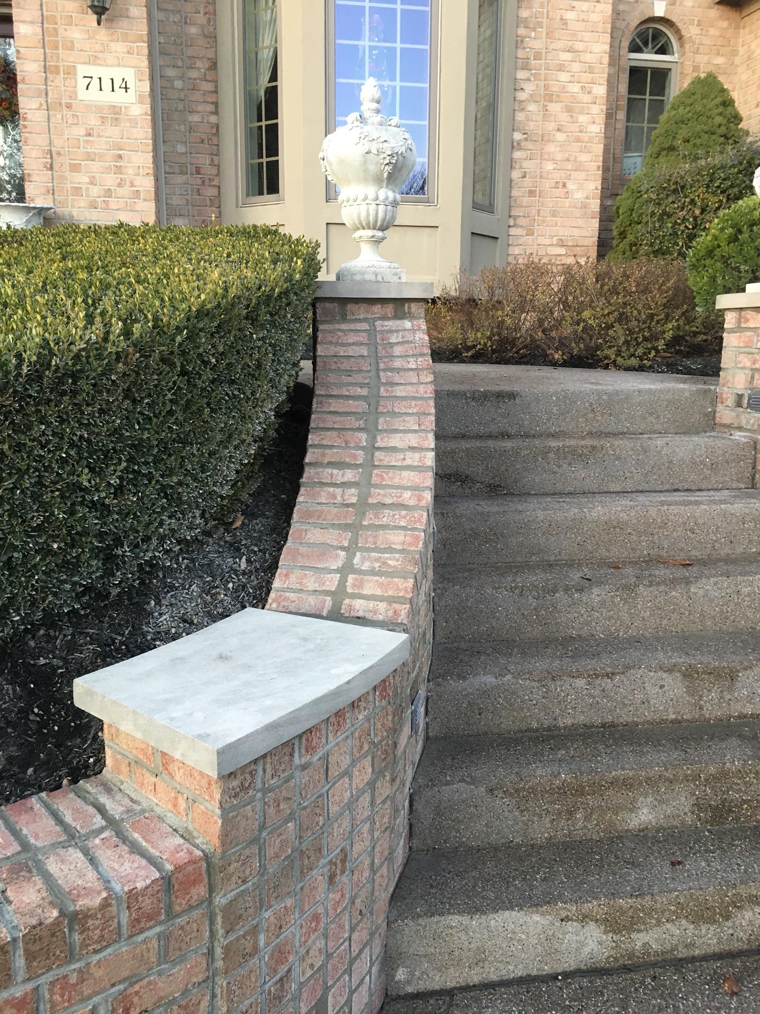Brick steps leading to a house with a brick wall and a decorative urn.