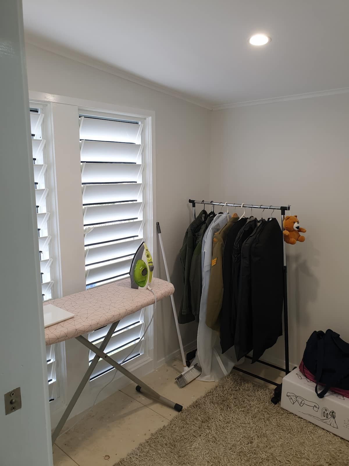 A Room With Clothes Hanging on Racks and an Ironing Board — Gaspen Builders & Carpenters in Kirwan, QLD