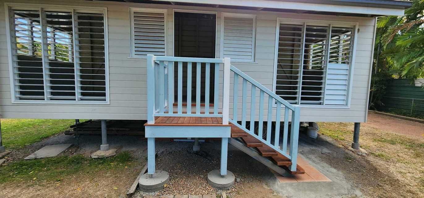 A Small White House With a Blue Porch and Stairs — Gaspen Builders & Carpenters in Kirwan, QLD