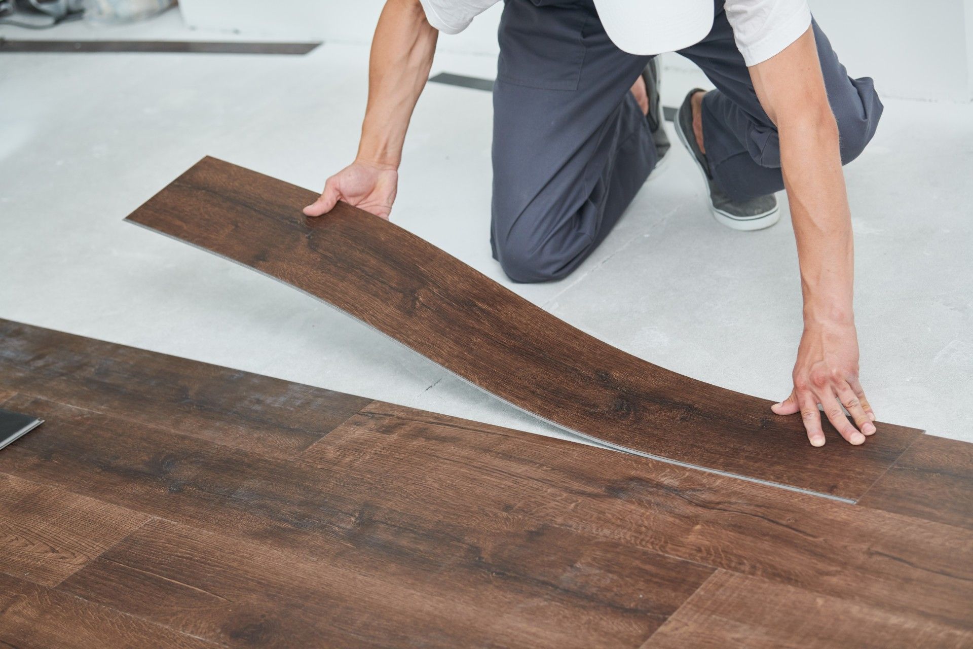 A man is kneeling down while installing a wooden floor.