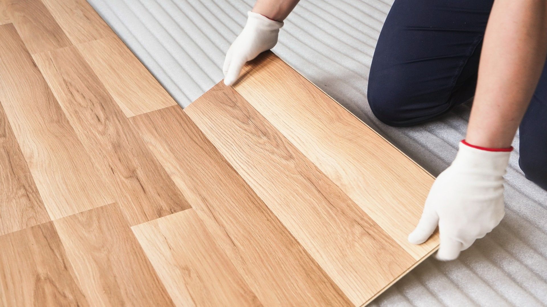 A person is installing a wooden floor in a room.