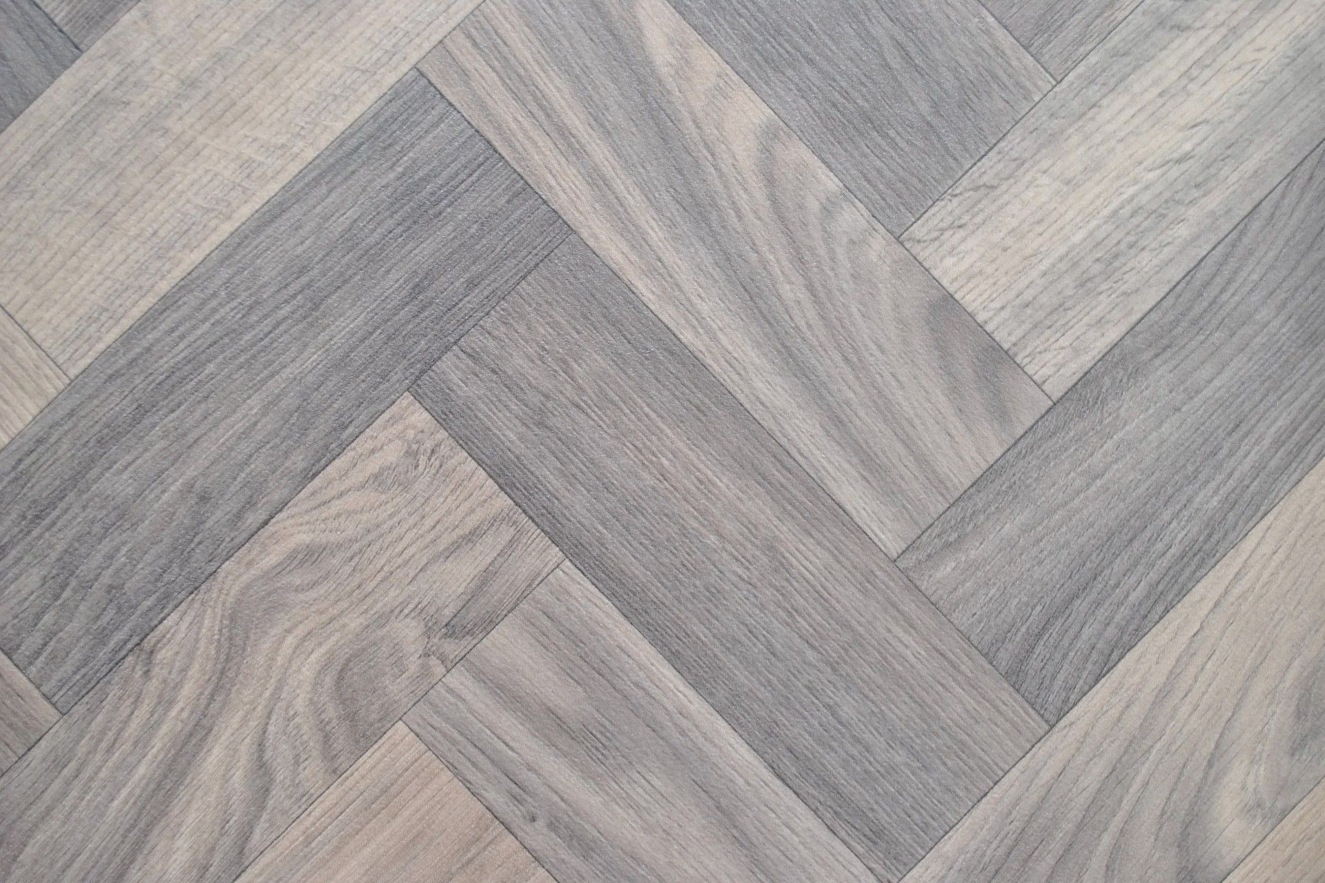 A close up of a wooden floor with a herringbone pattern.